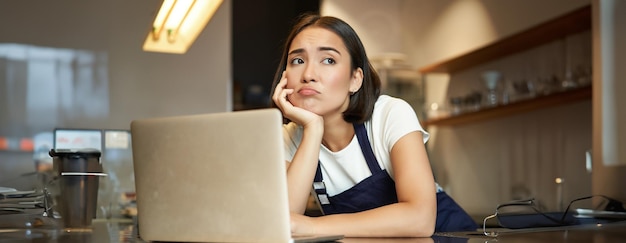 Portrait of korean woman barista in cafe looking sad and frowning grimacing disappointed while