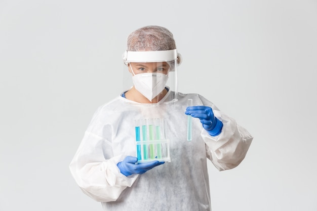 백신 샘플과 함께 테스트 튜브를 들고 개인 보호 장비에 실험실 기술, 과학자 또는 의사의 초상화, 치료법 검색
