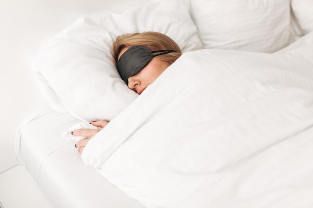 Portrait of lady wearing black eyes mask while sleeping in bed at home