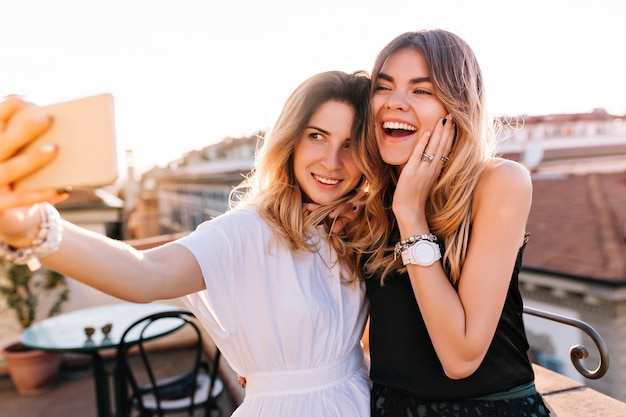 Portrait of laughing friends enjoying weekend together and making selfie on morning city