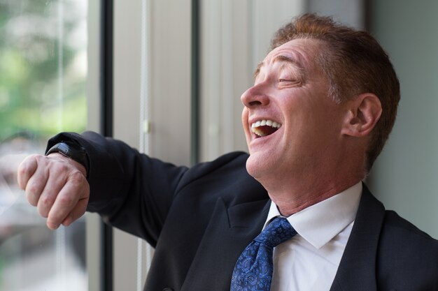 Portrait of laughing senior businessman at window