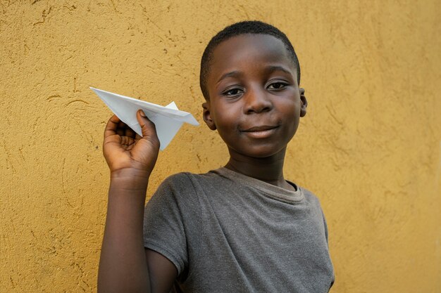 Портрет маленького африканского мальчика, играющего с самолетом