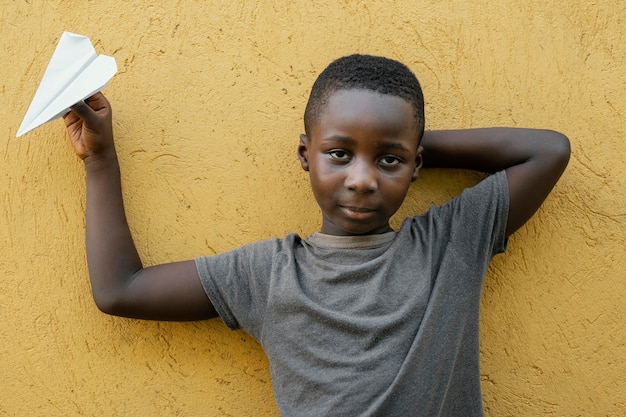 Foto gratuita ritratto piccolo ragazzo africano che gioca con l'aeroplano