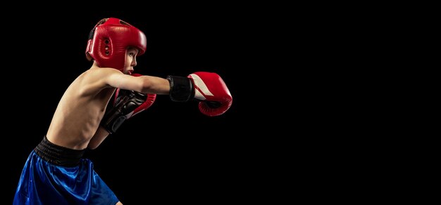 Portrait of little boy child training boxing isolated over black studio background Little sportsman