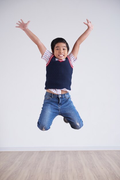 Portrait of little boy jumping happily high in the air