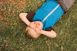 Free photo portrait of a little boy lying in a pretty garden setting