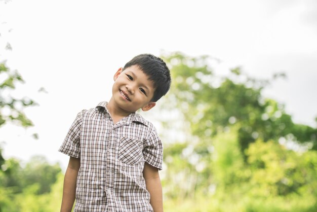 Портрет маленького мальчика, стоя в природный парк, улыбка на камеру.