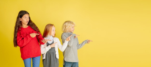 Portrait of little caucasian children with bright emotions isolated on yellow