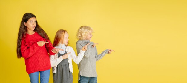 黄色に分離された明るい感情を持つ小さな白人の子供たちの肖像画