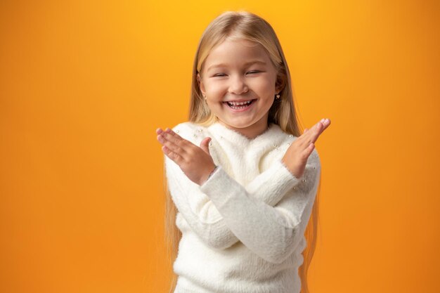 Portrait of little child girl with crossed arms against yellow background