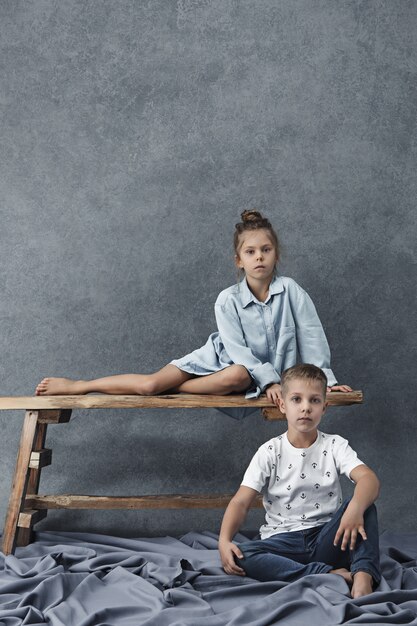 A portrait of little girl and a boy on the gray wall