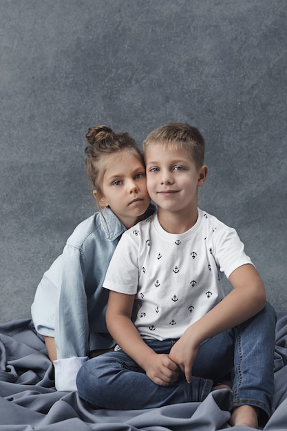 A portrait of little girl and a boy on the gray wall