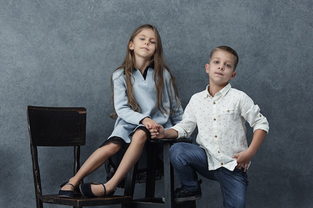 A portrait of little girl and a boy on the gray wall