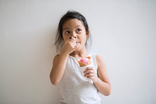 Portrait of little girl eating ice cream with good feeling