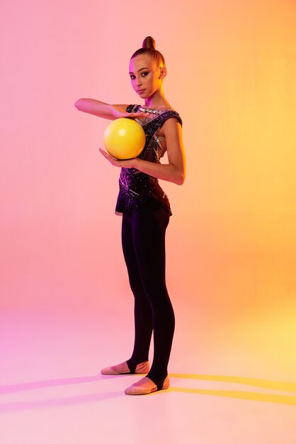 Portrait of little girl, rhythmic gymnastics artist training isolated on colored