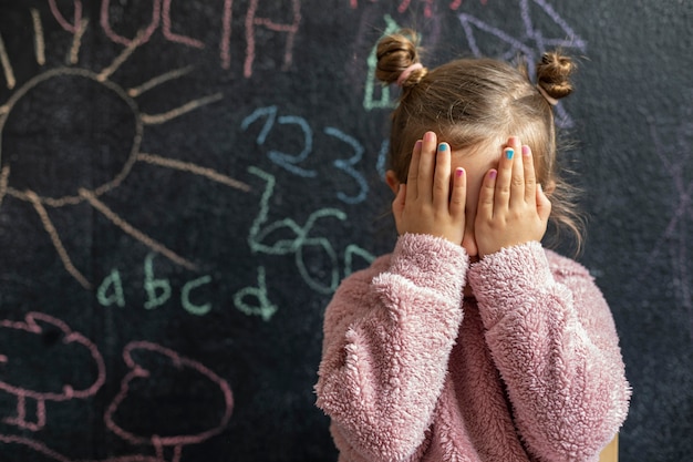 Free photo portrait little girl upset covering her face