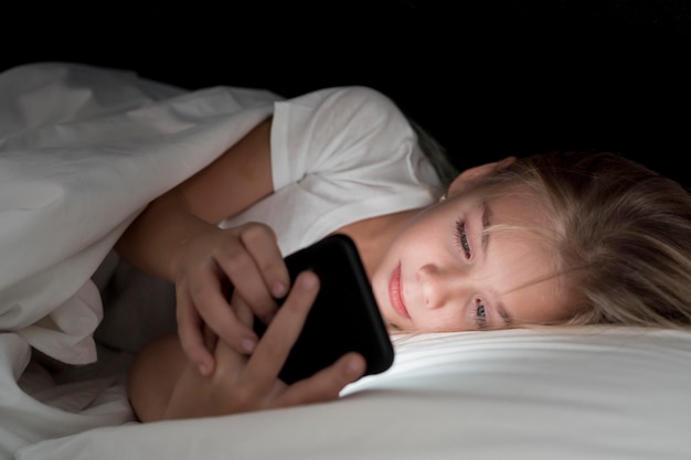 Free photo portrait little girl using phone at night