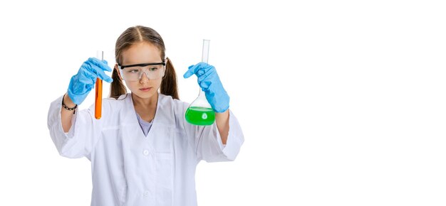 Portrait of little girl in white gown as chemist scientist doing experiment with multicolored chemical fluid in laboratory isolated on white background