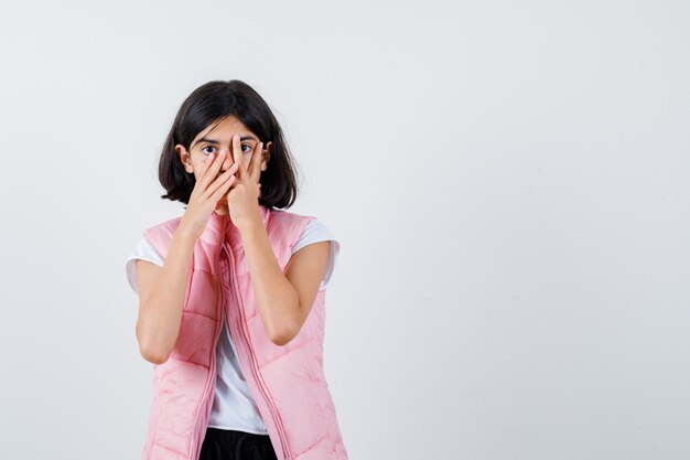 Portrait of a little girl in white t-shirt and puffer vest covering the face