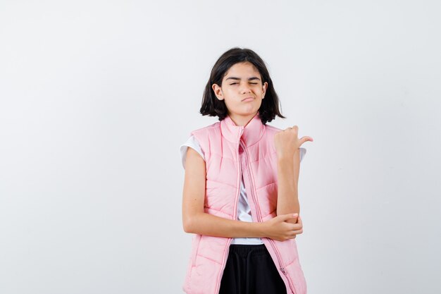 Portrait of a little girl in white t-shirt and puffer vest pointing right