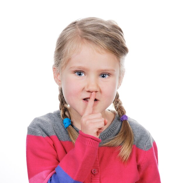 Portrait of little girl with silence gesture over white space