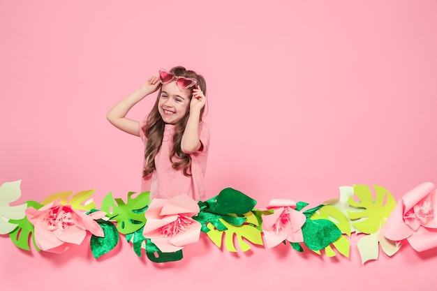 Portrait of a little girl with sunglasses on a pink wall