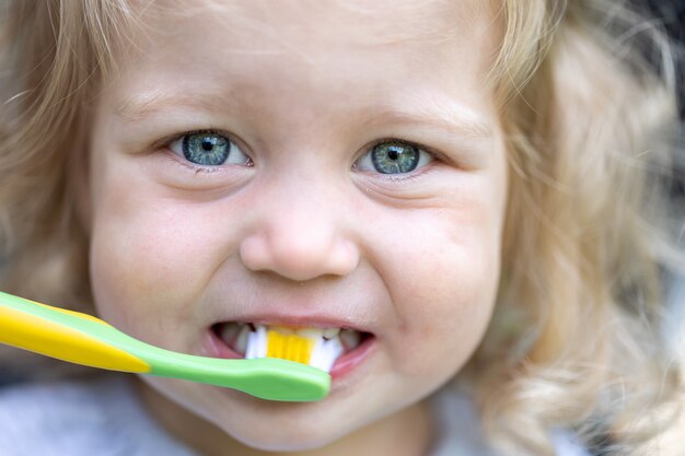 歯ブラシを持った少女の肖像画、子供は彼の歯を磨きます。