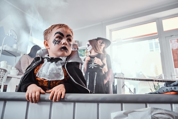 Portrait of little gloomy boy in Halloween costume vampire at festive party.