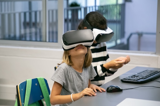 Portrait of little kids using VR headsets and having fun