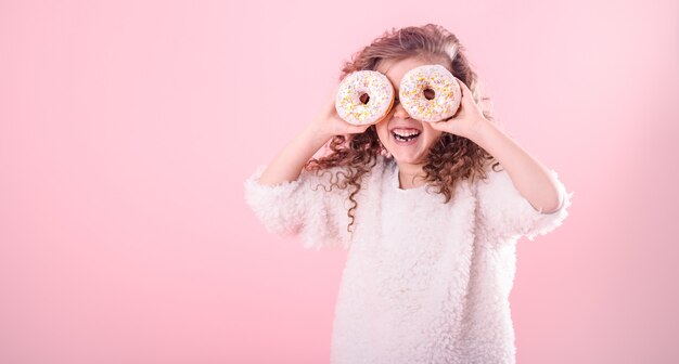 Portrait of a little smiling girl with donuts