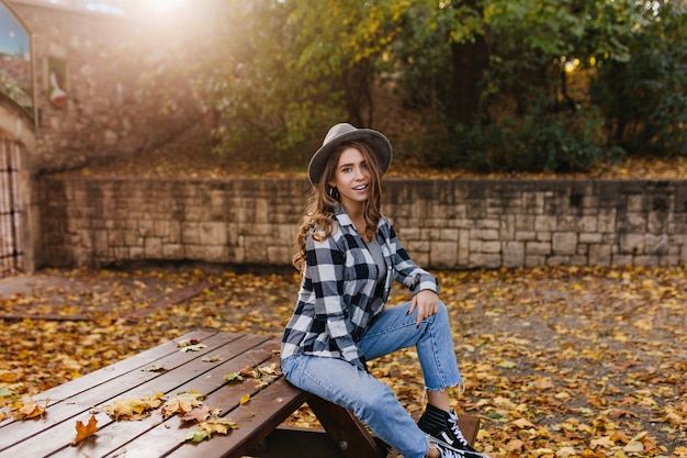 黄金の葉に囲まれた公園に座っている悲しい笑顔と孤独な少女の肖像画