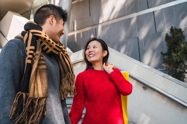 Portrait of lovely Asian couple enjoying shopping and having fun together in mall.