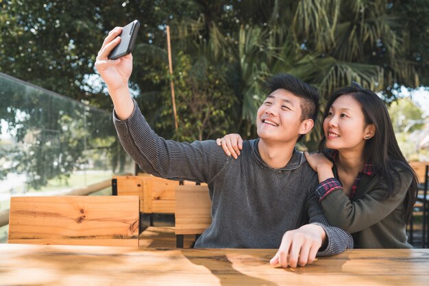 Портрет милой азиатской пары, хорошо проводящей время и делающей селфи с мобильным телефоном в кафе.