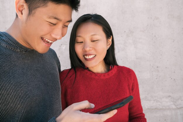 Portrait of lovely asian couple looking at the mobile phone while spending good time together. 