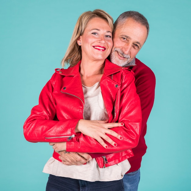 Portrait of lovely mature couple looking at camera against turquoise background