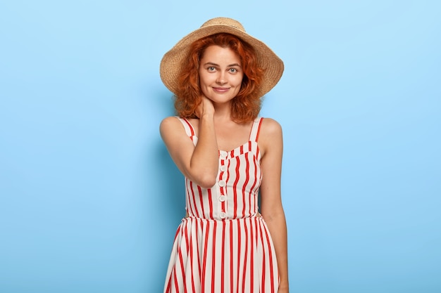 Ritratto di bella giovane donna con i capelli allo zenzero in posa in abito estivo e cappello di paglia