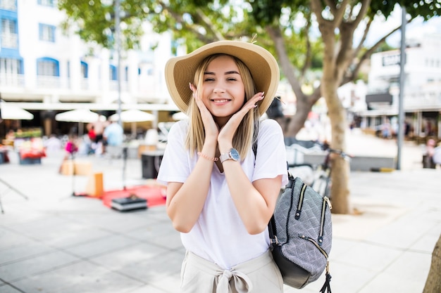 あごに触れているカメラを見て歯を見せる晴れやかな笑顔で素敵な若い女性の肖像画