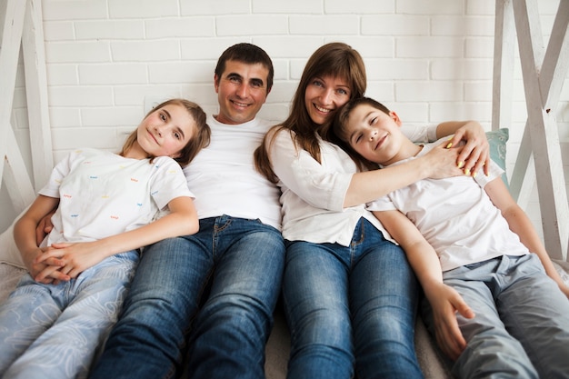 Portrait of loving family lying on bed looking at camera in bedroom