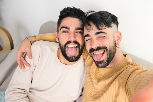 Portrait of loving homosexual couple sticking out their tongue out