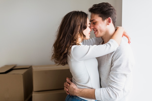 Portrait of loving young couple embracing standing in front of cardboard boxes