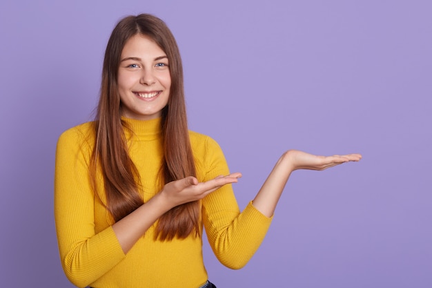 Foto gratuita ritratto di magnifica adorabile ragazza adorabile in camicia gialla casual, che punta da parte con due palme