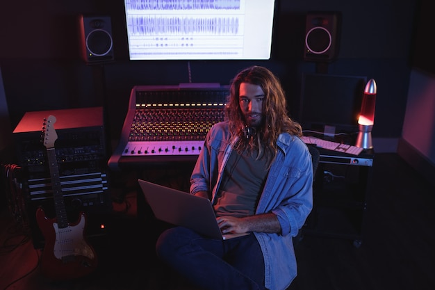 Portrait of male audio engineers using laptop