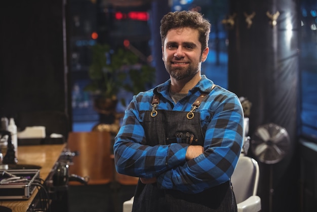 Free photo portrait of male barber standing with arm crossed