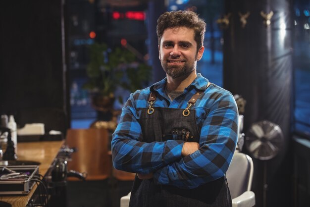 Portrait of male barber standing with arm crossed