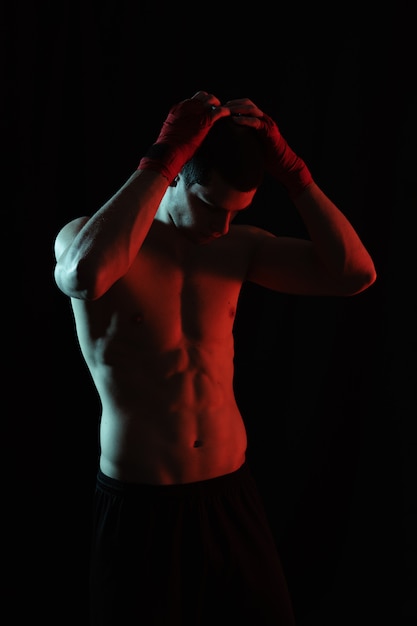 Портрет мужчины боксер позирует в красном и белом свете