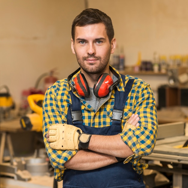 Free photo portrait of a male carpenter standing with his arms crossed