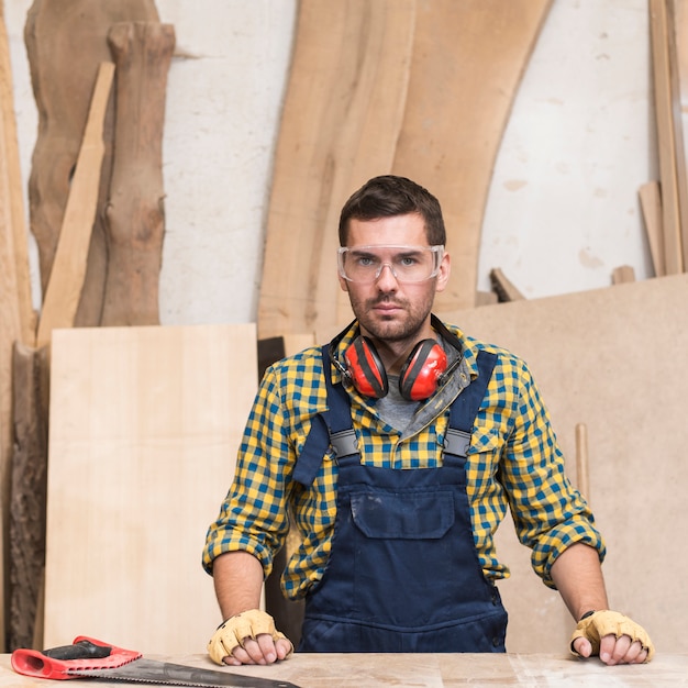 Free photo portrait of a male carpenter wearing ear defender around his neck looking at camera
