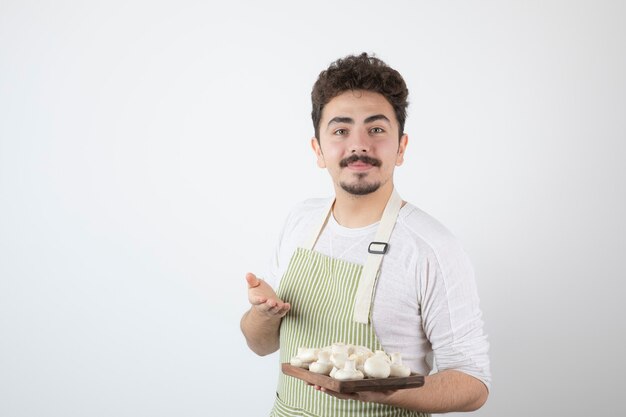 흰색에 생 버섯을 보여주는 남성 요리사의 초상화