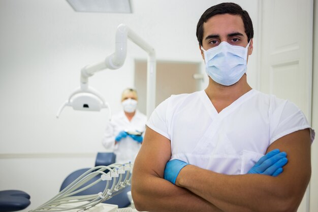 Портрет мужчины стоматолог, стоя со скрещенными руками
