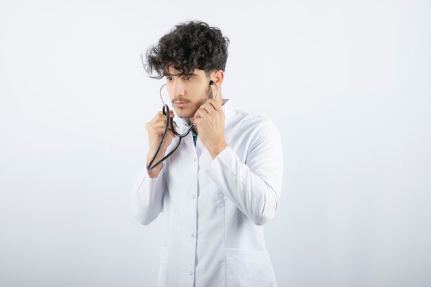 Portrait of a male doctor holding a stethoscope and listening . 